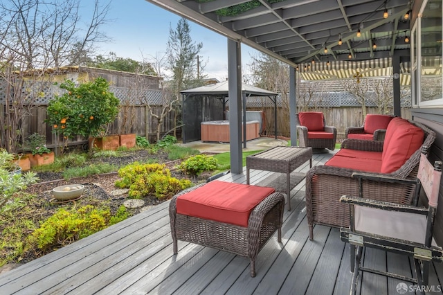 wooden deck with a hot tub, a gazebo, and an outdoor hangout area