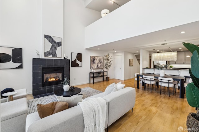 living room featuring a fireplace, a high ceiling, and light hardwood / wood-style floors