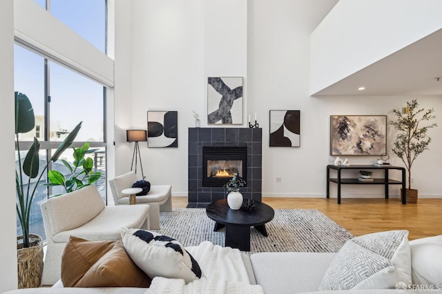 living room featuring hardwood / wood-style flooring, a high ceiling, and a fireplace