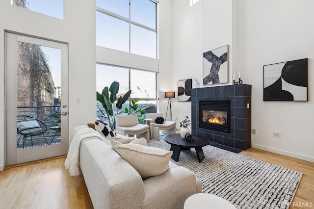 living room with a tiled fireplace, a high ceiling, and hardwood / wood-style floors