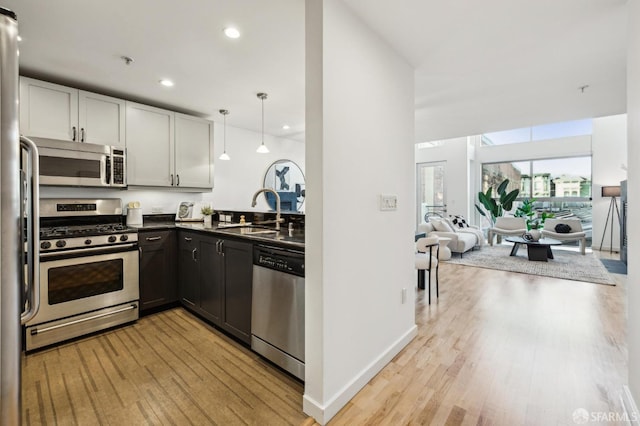 kitchen with light hardwood / wood-style floors, sink, white cabinetry, hanging light fixtures, and stainless steel appliances