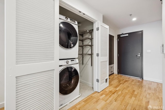 laundry room featuring hardwood / wood-style floors, stacked washer and dryer, and a barn door