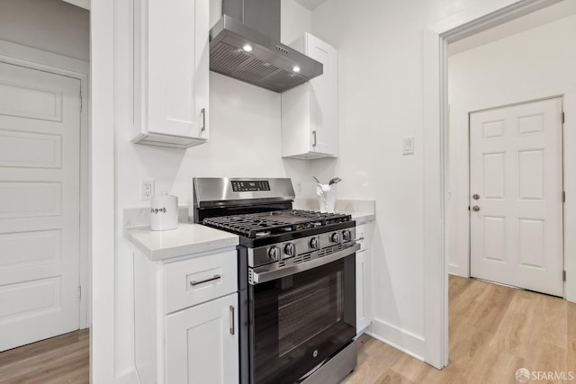 1015 Key Ave, San Francisco, CA 94124 - kitchen with stainless steel gas stove, wall chimney range hood, light wood-style flooring, light countertops, and white cabinets