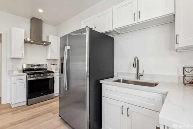 1015 Key Ave, San Francisco, CA 94124 - kitchen featuring stainless steel appliances, wall chimney range hood, white cabinets, light wood-style flooring, and recessed lighting