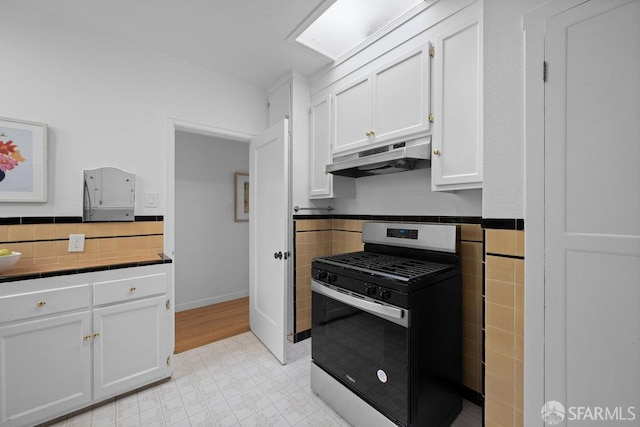 57 Masonic Ave, San Francisco, CA 94118 - kitchen featuring stainless steel gas stove, under cabinet range hood, tile counters, white cabinetry, and light flooring
