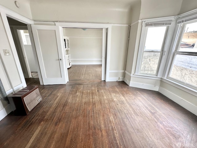 interior space featuring dark wood-style floors, a wall mounted AC, and baseboards