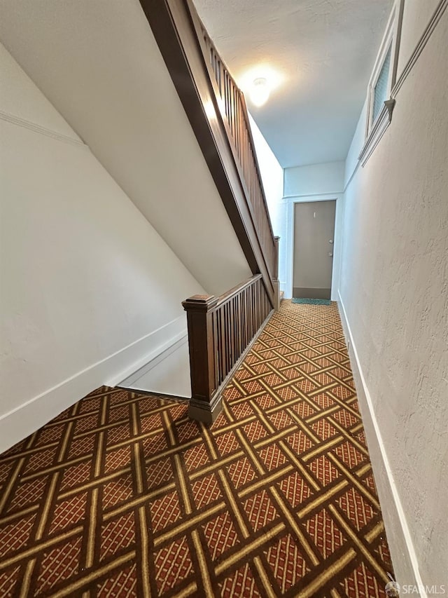 hallway with baseboards and a textured wall