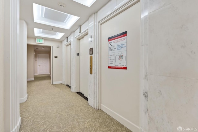 hall featuring carpet floors, a skylight, and baseboards