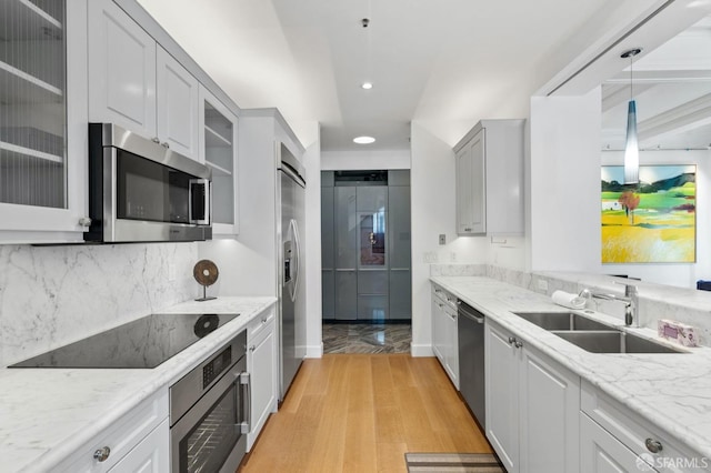 kitchen with light wood-style flooring, recessed lighting, a sink, backsplash, and appliances with stainless steel finishes