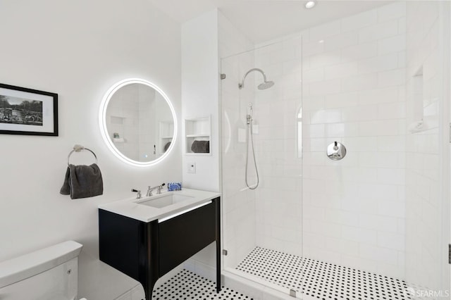 bathroom featuring a tile shower, vanity, and toilet