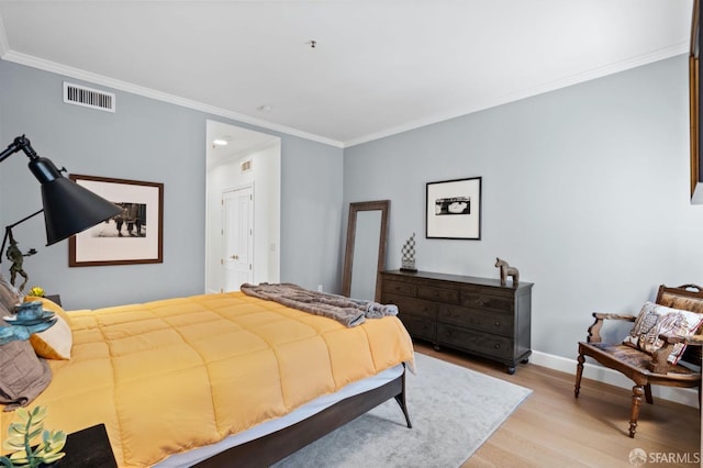 bedroom featuring crown molding, light wood-style floors, visible vents, and baseboards