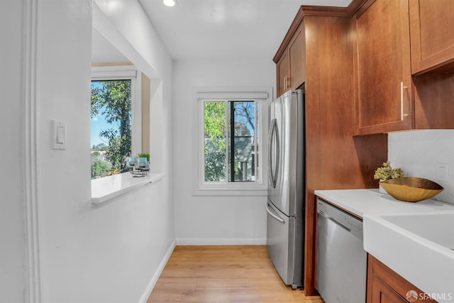 kitchen featuring decorative backsplash, light wood-type flooring, stainless steel appliances, and sink