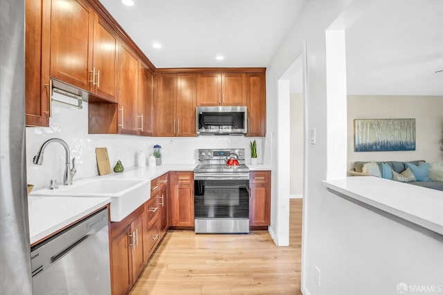 kitchen with light wood-type flooring, sink, appliances with stainless steel finishes, and tasteful backsplash