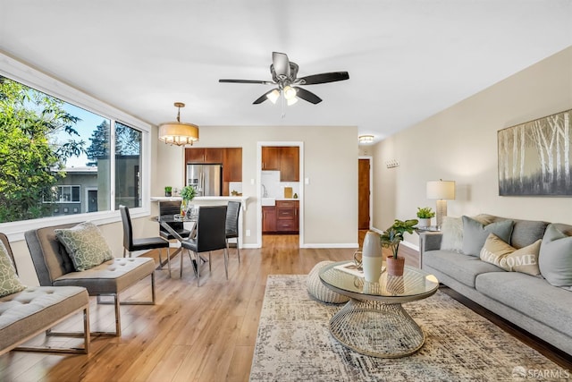 living room featuring ceiling fan with notable chandelier and light hardwood / wood-style flooring