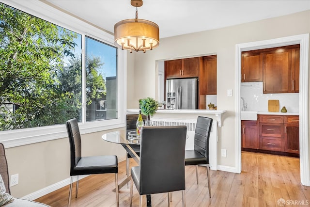 dining space with plenty of natural light, light wood-type flooring, and sink