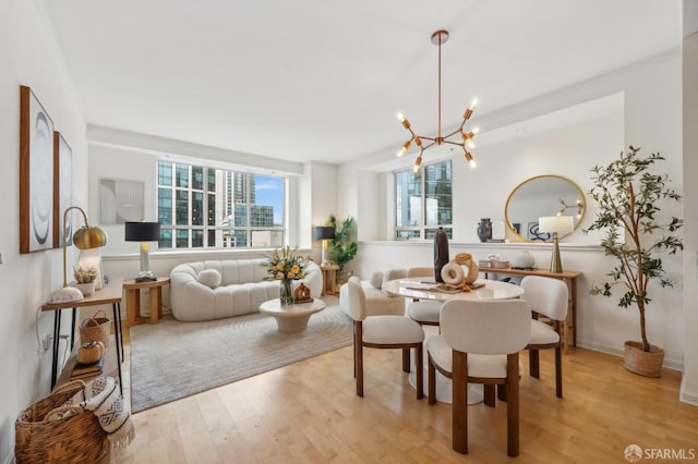 dining room with a notable chandelier, ornamental molding, and light hardwood / wood-style flooring