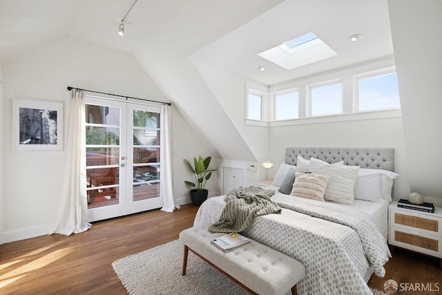 bedroom with lofted ceiling with skylight, track lighting, baseboards, and wood finished floors