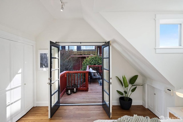 foyer entrance with french doors, vaulted ceiling, light wood-style flooring, and track lighting