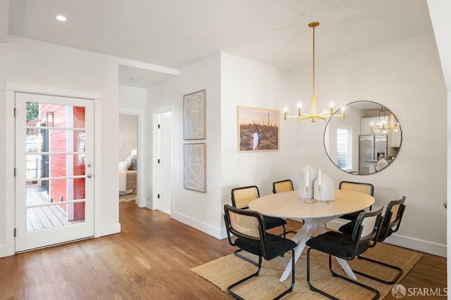 dining room with a chandelier, plenty of natural light, and wood finished floors