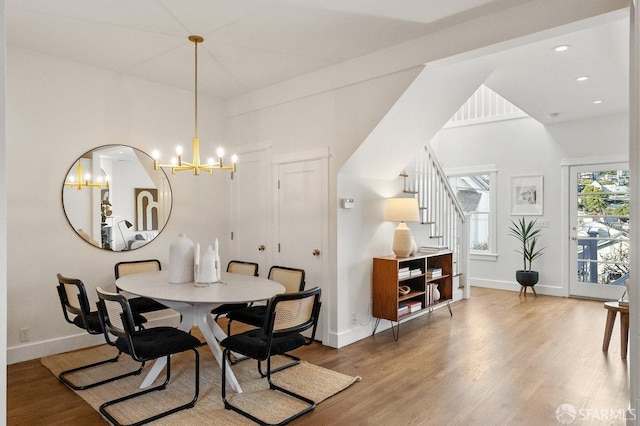 dining room featuring light wood-type flooring, stairs, baseboards, and a notable chandelier