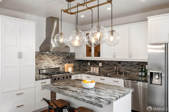 kitchen with appliances with stainless steel finishes, a sink, wall chimney exhaust hood, and tasteful backsplash