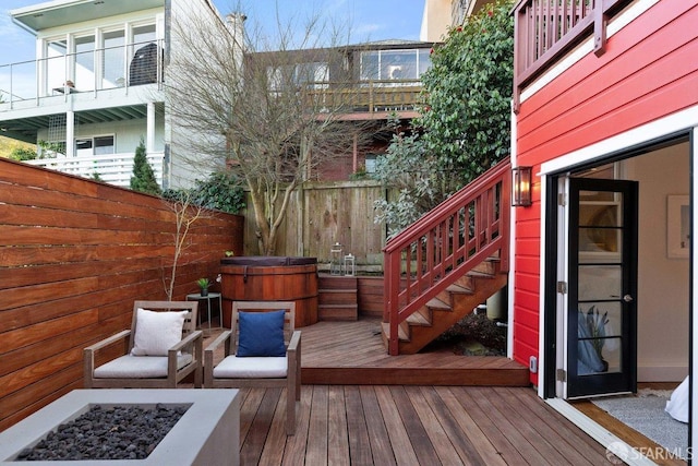 wooden terrace featuring an outdoor fire pit, fence, and stairway