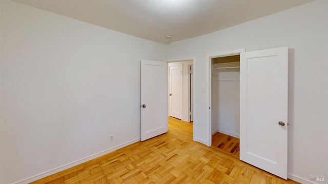 unfurnished bedroom with light parquet floors and a closet
