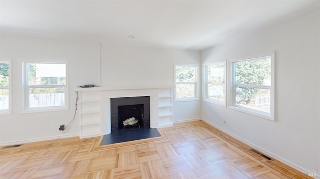 unfurnished living room featuring light parquet floors and a fireplace
