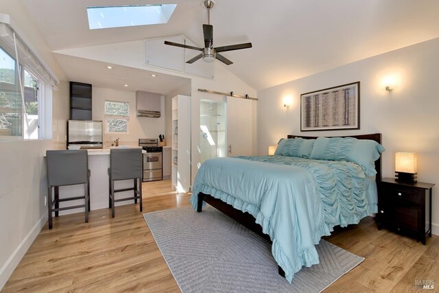 bedroom featuring light hardwood / wood-style floors, lofted ceiling with skylight, fridge, and a barn door