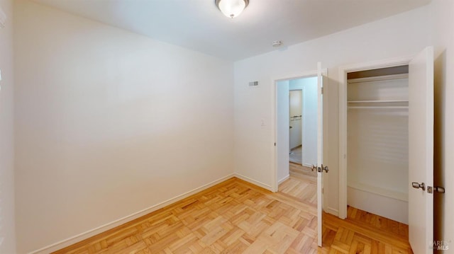 unfurnished bedroom featuring light parquet floors and a closet