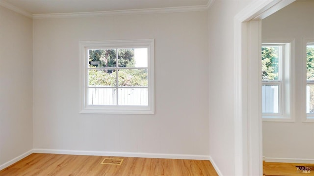 unfurnished room featuring hardwood / wood-style flooring, ornamental molding, and a wealth of natural light