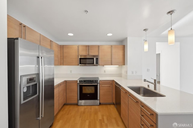 kitchen featuring sink, decorative light fixtures, light hardwood / wood-style floors, kitchen peninsula, and stainless steel appliances