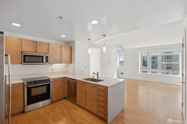 kitchen featuring sink, kitchen peninsula, stainless steel appliances, and hanging light fixtures