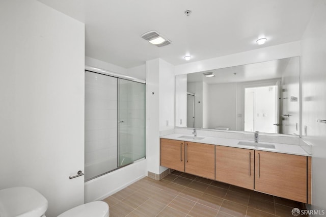 full bathroom featuring shower / bath combination with glass door, tile patterned flooring, vanity, and toilet