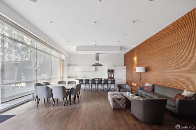 dining room featuring dark hardwood / wood-style floors, wooden walls, and sink