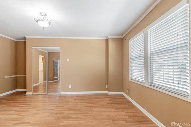 spare room featuring ornamental molding and light wood-type flooring