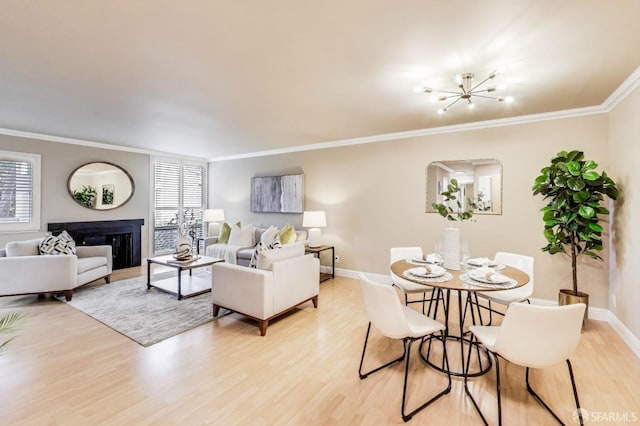 living area with baseboards, ornamental molding, a fireplace, and light wood-style floors