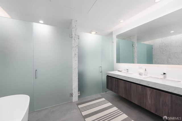 full bathroom featuring a sink, a freestanding tub, recessed lighting, and double vanity