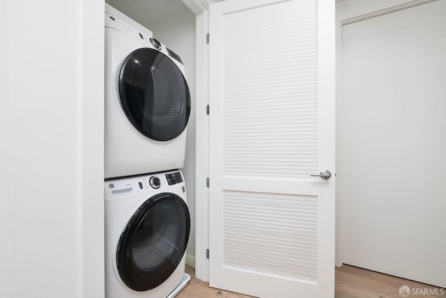 laundry area featuring light wood-type flooring, laundry area, and stacked washer and dryer