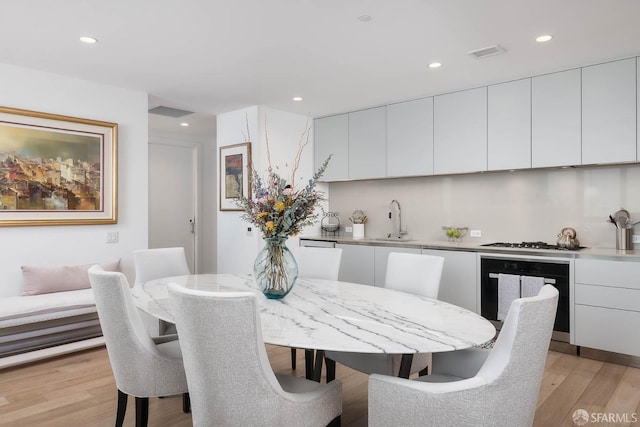 dining room featuring indoor wet bar, recessed lighting, visible vents, and light wood finished floors