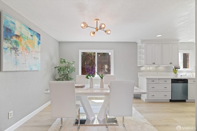 dining room featuring light wood-type flooring, a textured ceiling, and an inviting chandelier