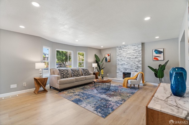 living room featuring a fireplace, light hardwood / wood-style floors, and a textured ceiling