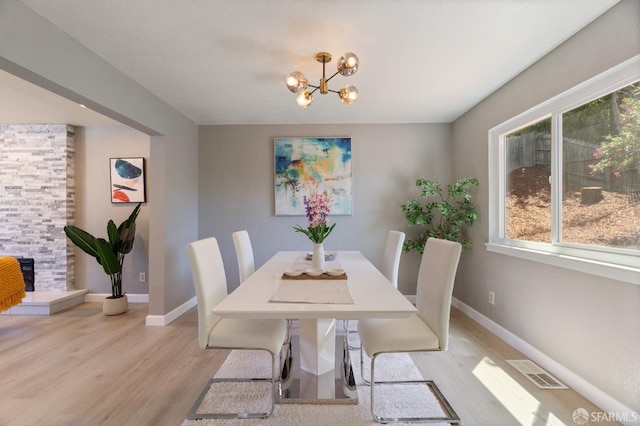 dining area with a chandelier, light hardwood / wood-style floors, and a fireplace