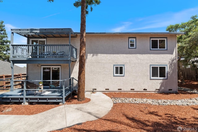 rear view of house featuring a balcony and a wooden deck