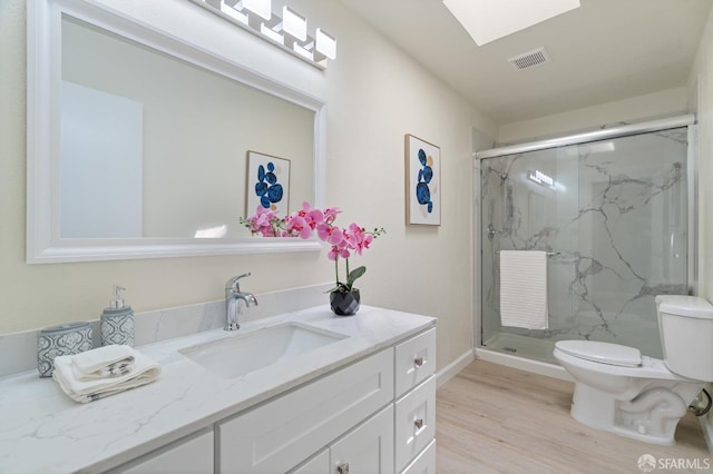 bathroom with vanity, a skylight, hardwood / wood-style flooring, toilet, and walk in shower