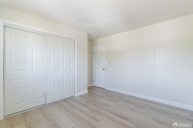 unfurnished bedroom with a textured ceiling, light hardwood / wood-style floors, and a closet