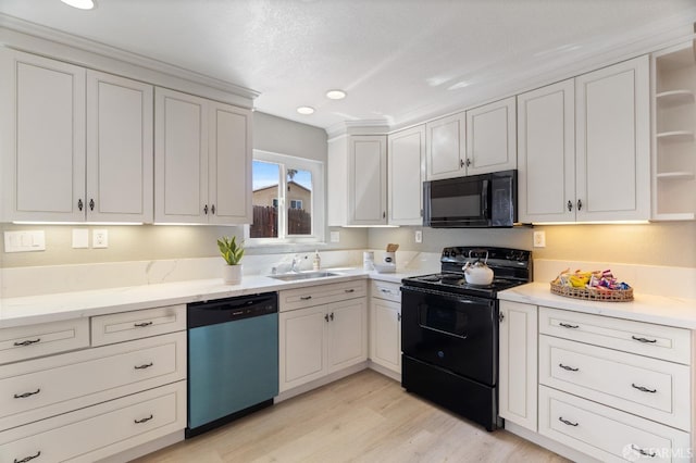 kitchen featuring white cabinets, light wood-type flooring, sink, and black appliances