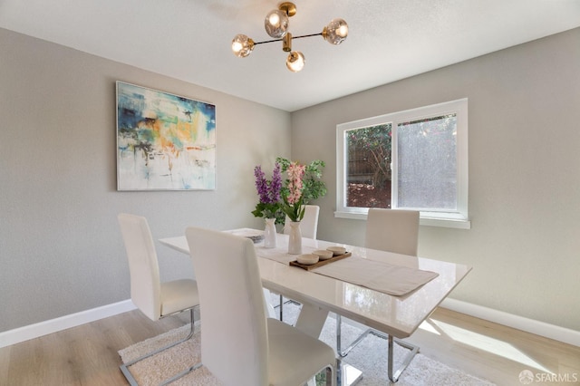 dining area with light hardwood / wood-style flooring and a chandelier