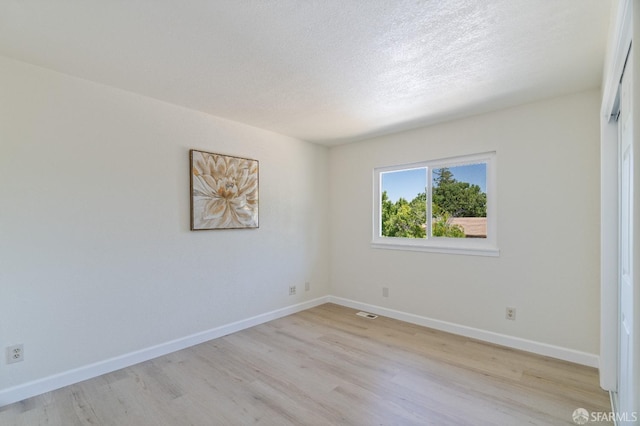 empty room featuring a textured ceiling and light hardwood / wood-style flooring