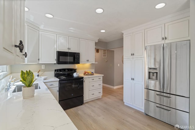 kitchen with black appliances, sink, light stone countertops, light wood-type flooring, and white cabinetry